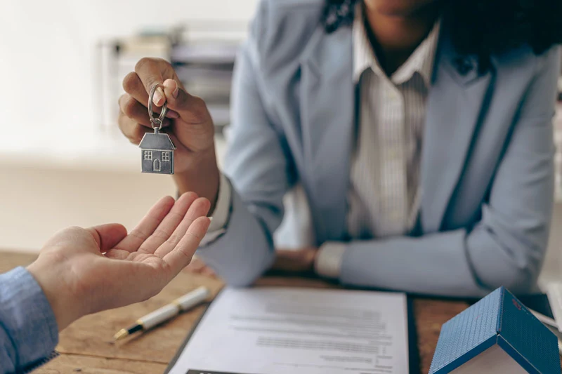 Close-up image of a woman giving house keys to a tenant.