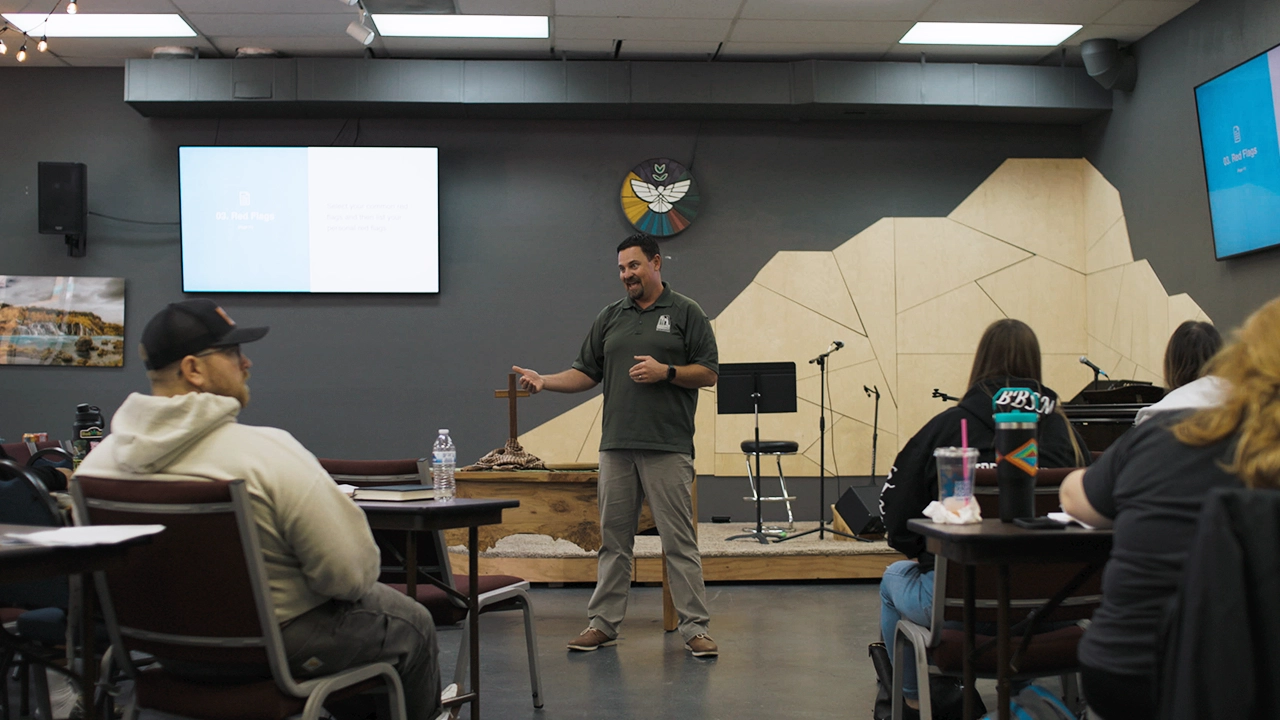 Image of Church @ the Park founder DJ Vincent standing in front of a classroom, addressing people sitting at desks.